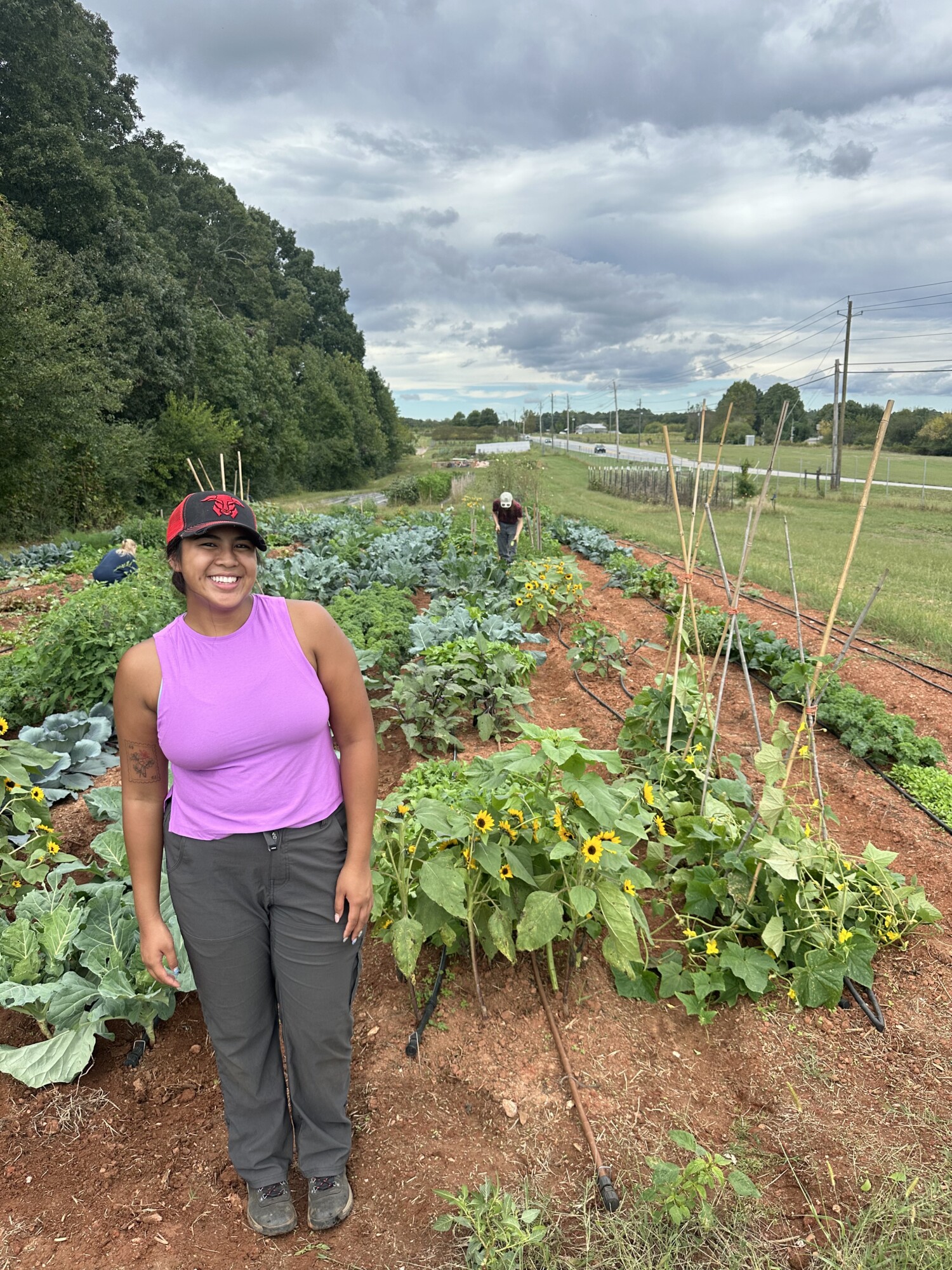 Supatcha, social media coordinator standing in front of a plot